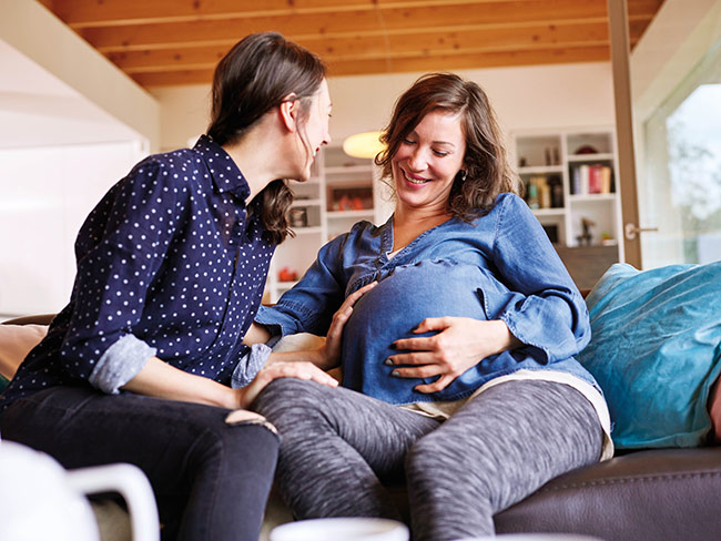 pregnant woman sitting on sofa talking with another woman