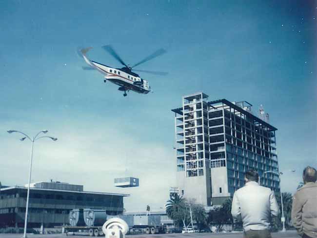 Helicopter lifting HVAC machinery to rooftop of new Oakland hospital, 1971