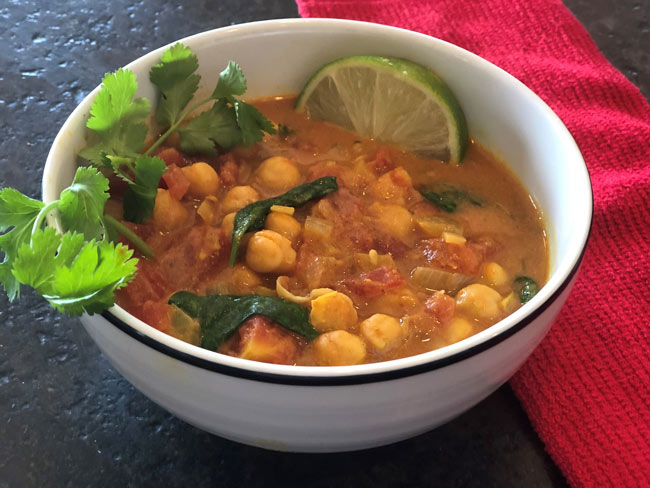 Chickpeas and crushed tomatoes in curry sauce, garnished with greens