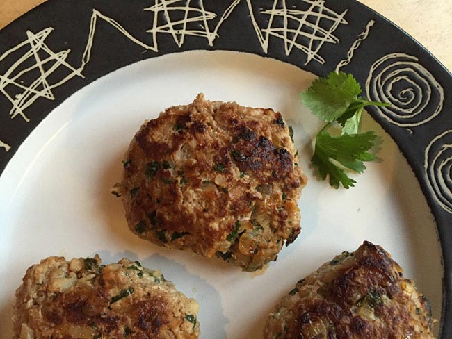 Asian-inspired turkey burgers on a white plate with a black rim.