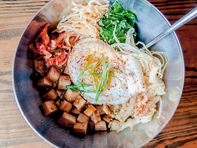 Bowl with bean sprouts, cubed tofu, bok choy, kimchi, spinach; topped with a fried egg.