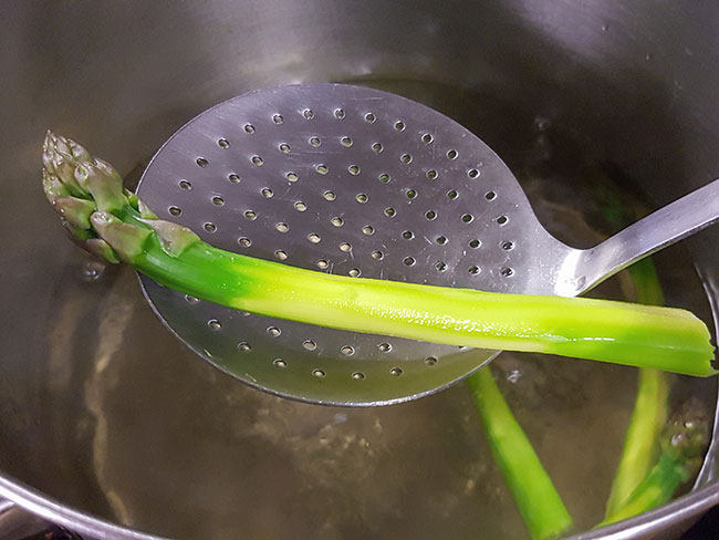 Blanching fresh, green asparagus in a stock pot.