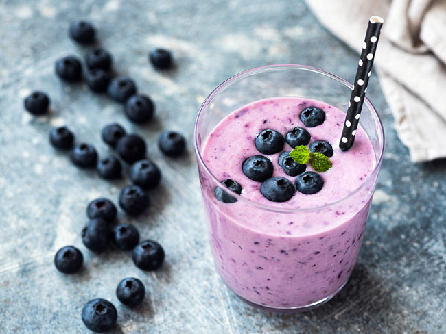 A top-down view of a blueberry smoothie, topped with fresh bluberries.