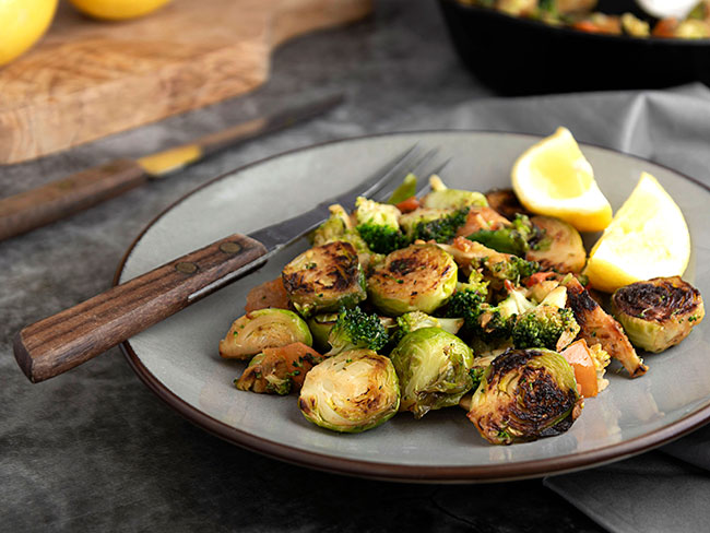 Roasted brussels sprouts and a fork on a grey plate.