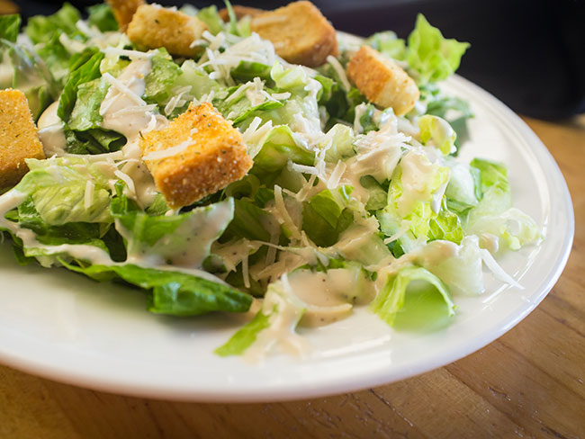 Fresh organic Caesar salad topped with grated asiago cheese and croutons.