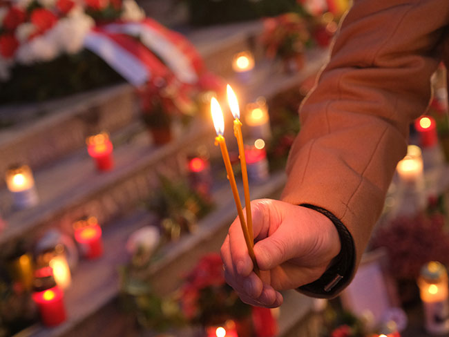 man's hand holding 2 candles for a candlelight vigil
