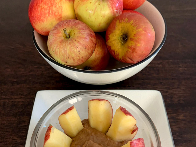 Bowl of apples and bowl containing caramel dip with apple slices.