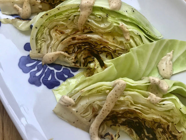 Cabbage wedges, charred, with chipotle lima crema, on plate.