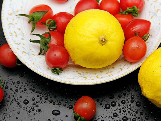Cherry tomatoes and lemons on a white plate.