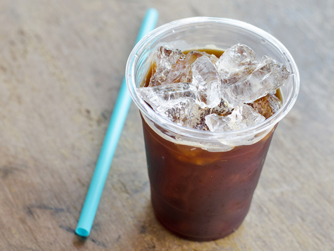 A class of cold brew with a straw on the side. 
