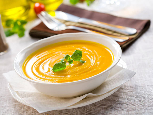 bowl of creamy butternut squash soup garnished with basil leaves
