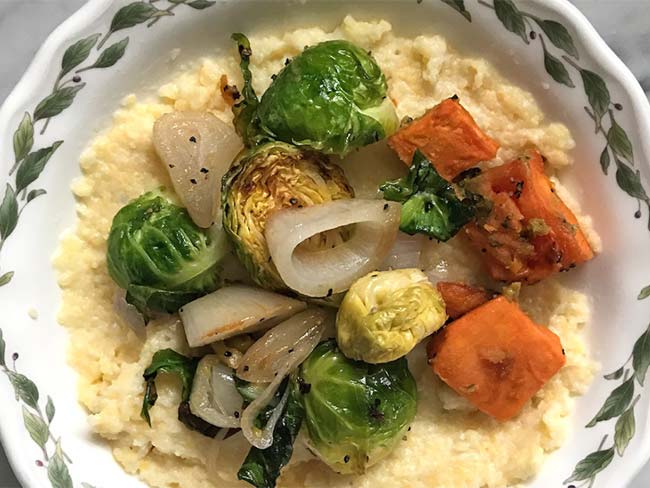Grits served with onions tomatoes and brussel sprouts