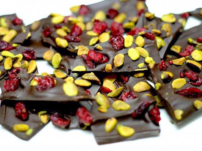 Dark chocolate bark with pistachios and dried cranberries on a white background.
