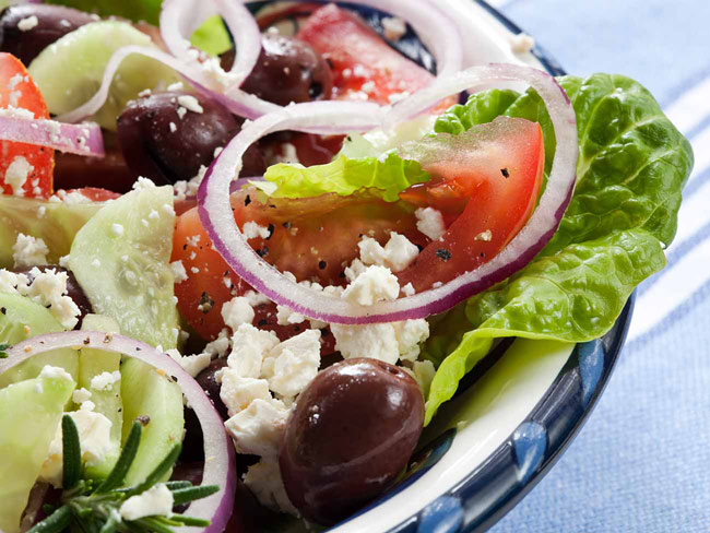 Bowl of greek salad with feta, tomato, red onion, and olives