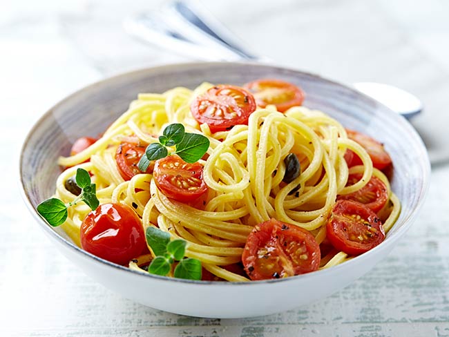 sliced tomato and basil spread over pasta