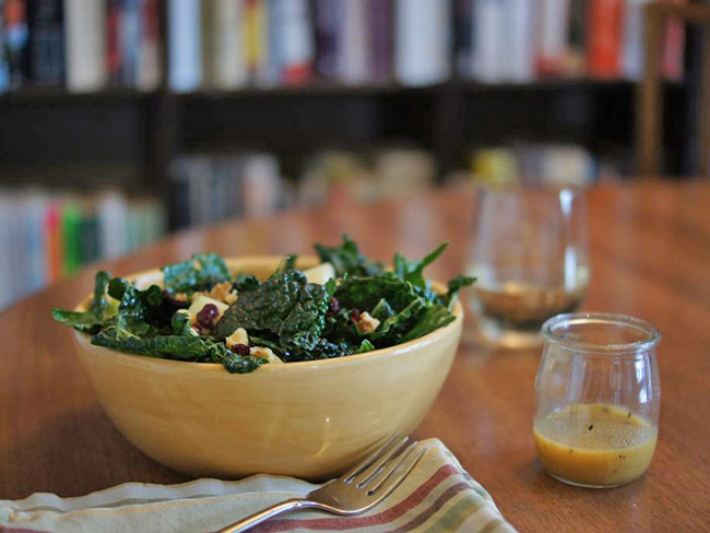 bowl of kale salad with diced apples, cranberries and pecans