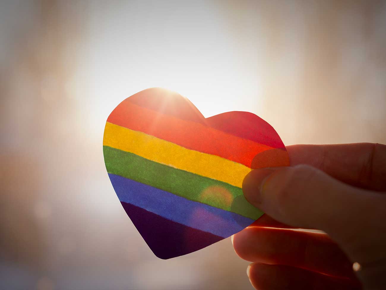 Hand holding a rainbow heart