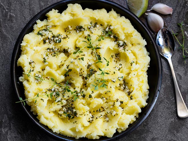 A bowl of mashed potatoes with olive oil, garlic and herbs.