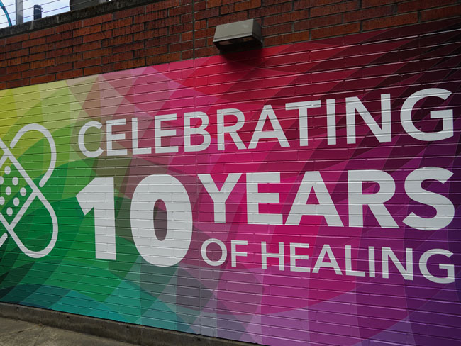 Mural painted on a brick wall, "Celebrating 10 years of healing"