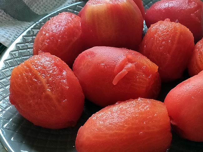 A plate full of peeled Roma tomatoes.