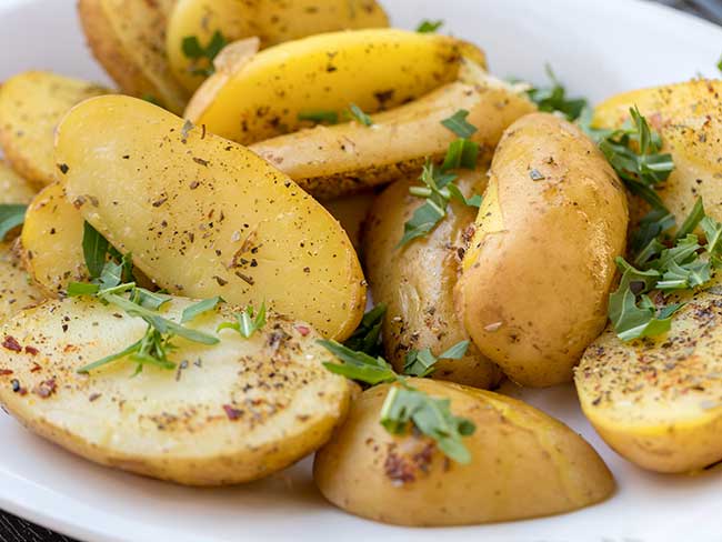 Russian fingerling potatoes with parsley on a white plate.