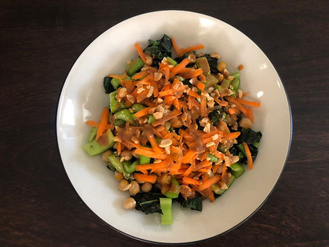 Overhead picture of grain bowl showing green, chopped carrots, and peanuts.