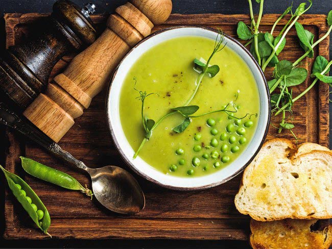 A bowl of spring pea soup with miso and tofu with thickly sliced toast on the side. 