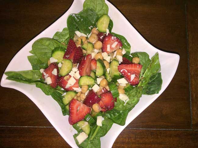 Baby spinach salad with chopped cucumbers, strawberries, garbanzo beans and crumbled feta cheese