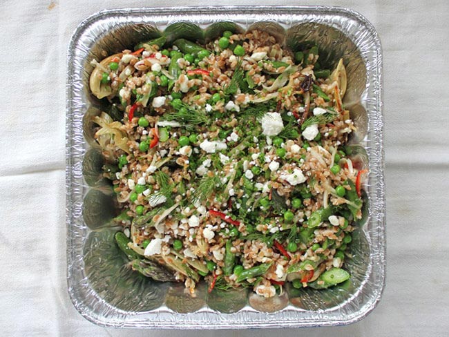 Summer Salad mixed with greens and goat cheese in a metal tray 