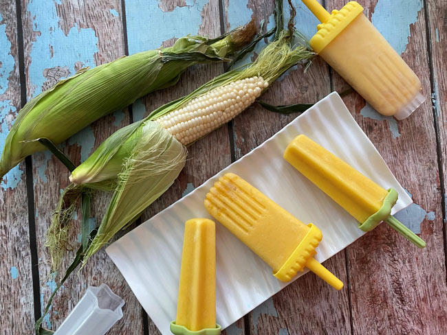 Overhead picture of corn on the cob in husks and corn ice pops