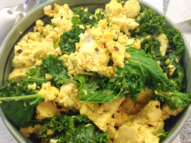Tofu that looks like scrambled eggs and kale mixed together in bowl