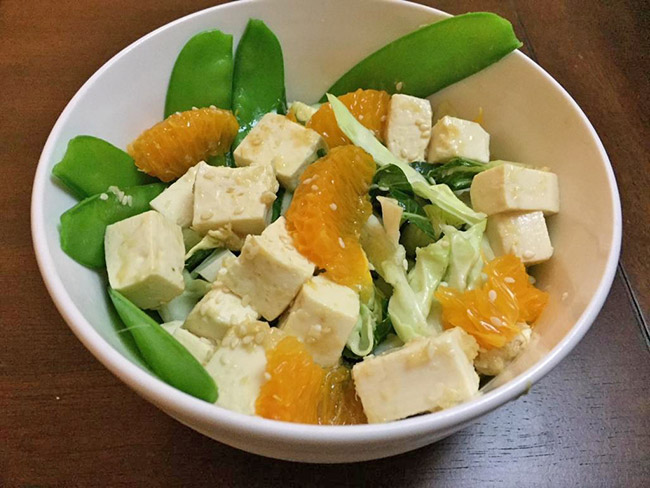 A bowl of Tofu salad with Napa cabbage, snap peas and Mandarin oranges.