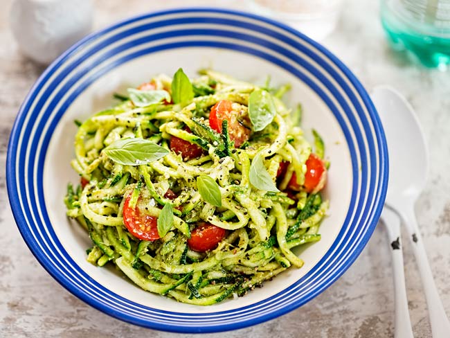 A bowl of spiralized zucchini with tomatoes and basil pesto